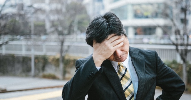 頭を抱えどうすっかな・・と思い悩む男性